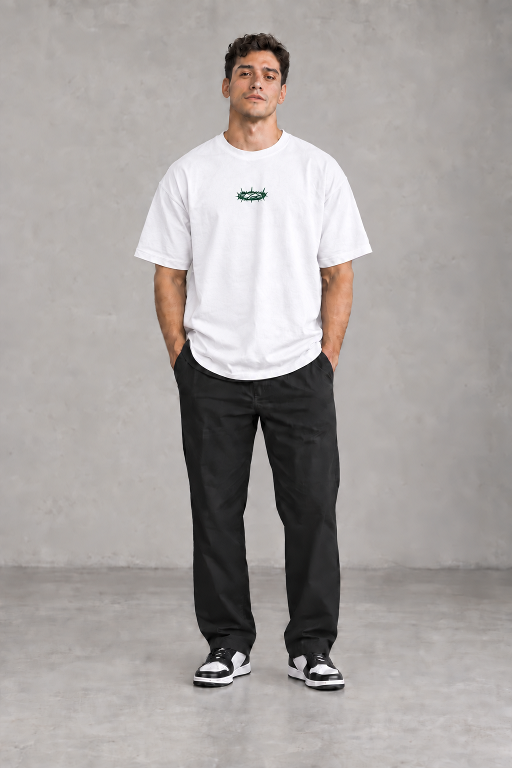 Männliches Model mit weißem GRÖẞTE LIEBE Signature-T-Shirt und mittiger dunkelgrüner Dornenkrone von vorne